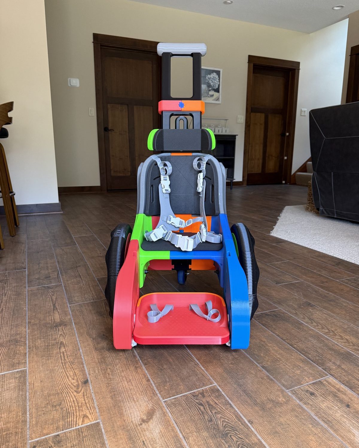 Toddler Mobility Trainer designed by MakeGood, blue chassis with carbon-fiber wheels and a five-point harness seat, printed by Warner3D.